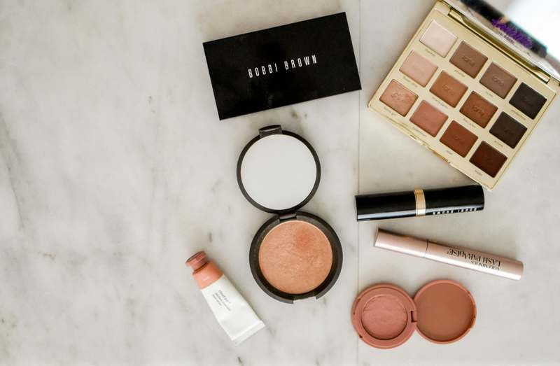 Minimalist white makeup table with gold stool, ring light, and organized skincare bottles